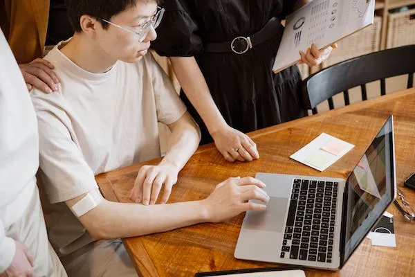 Creating an invoice template on a laptop with a colleague